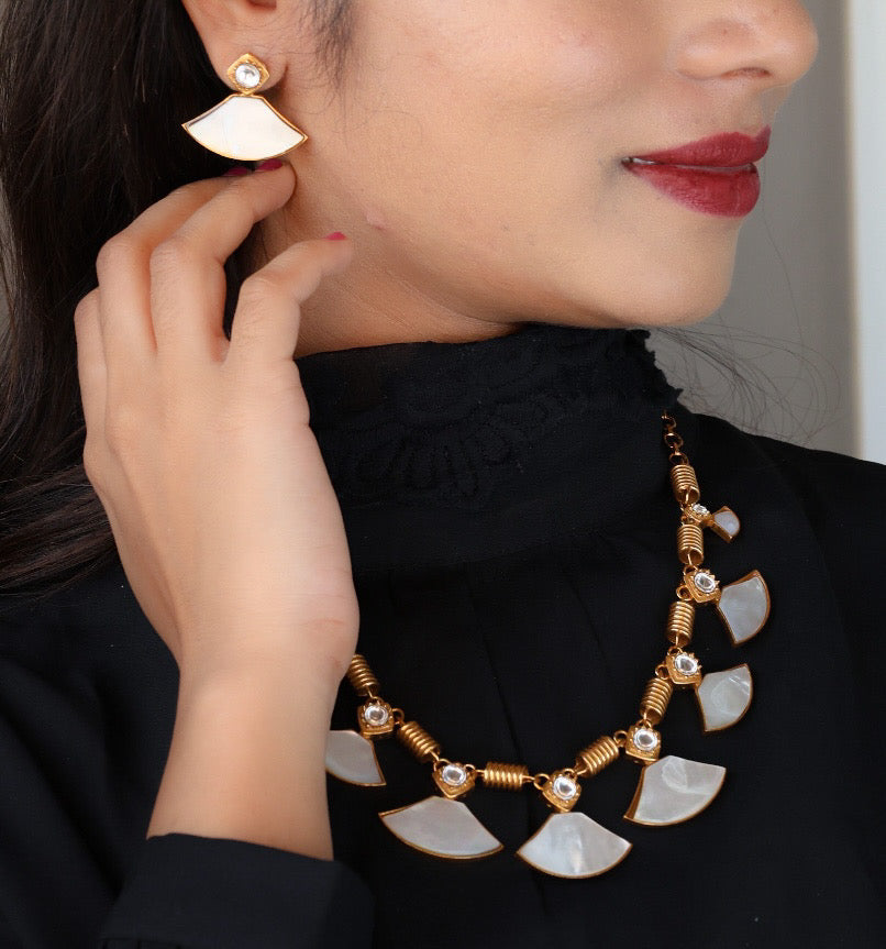Angled view of elegant necklace showing shell-like motif and shimmering enamel details