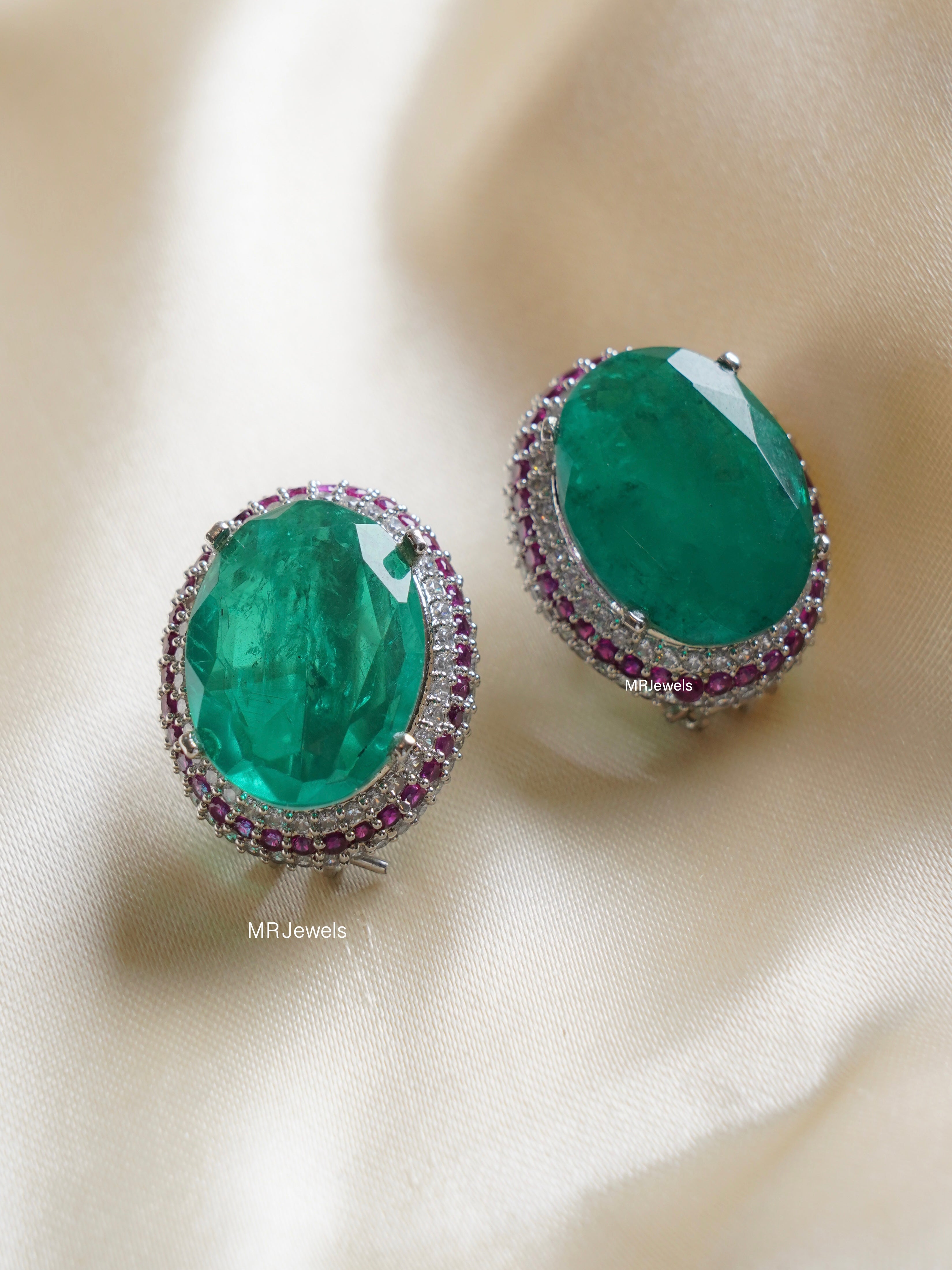 oversized clip‑on studs with emerald center and double halo of white and pink cz