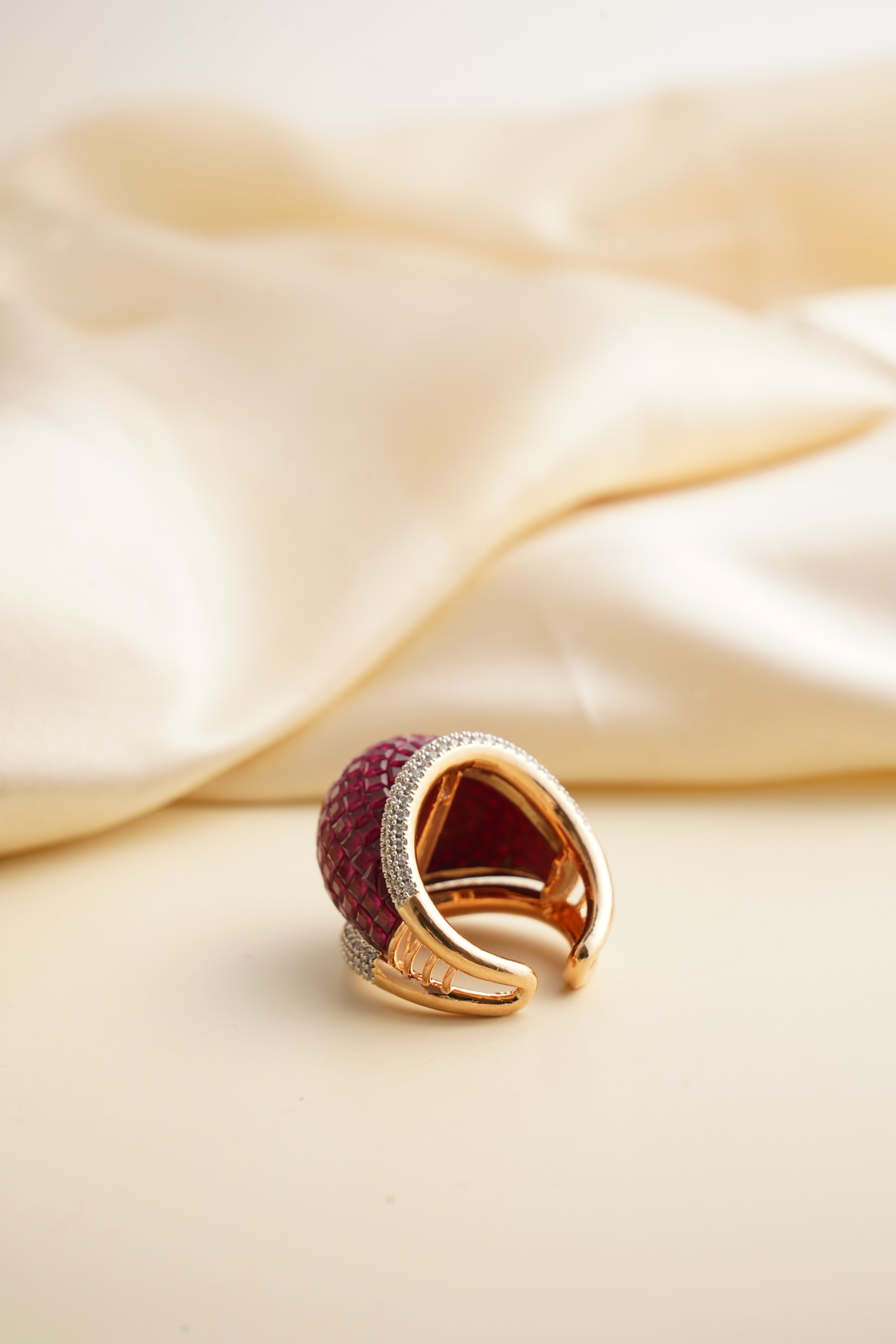 Close-up of ruby ring featuring zircon halo and sleek gold-plated band