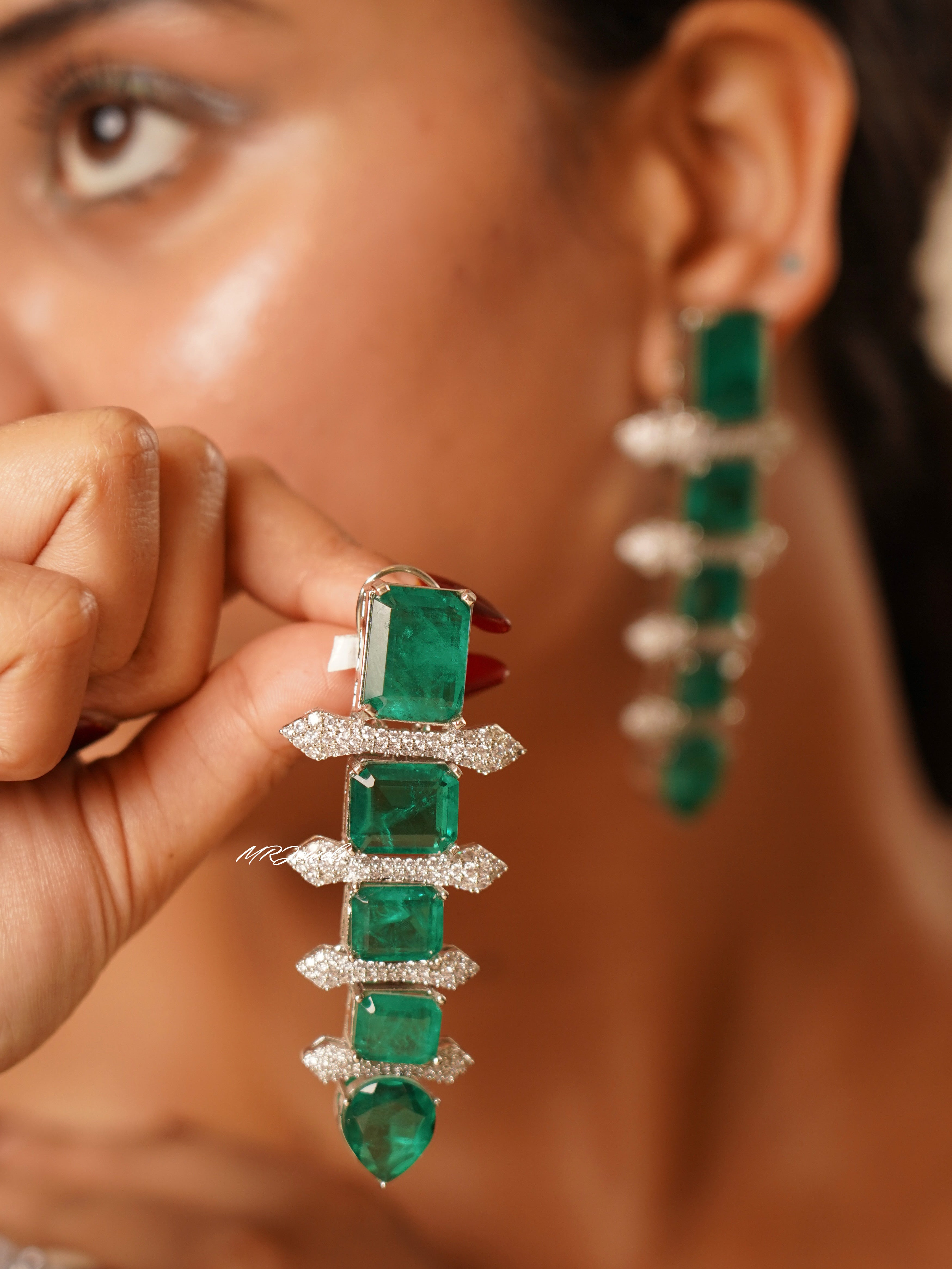 Emerald dynasty earrings with cascading green stones and shimmering diamond-like border accents