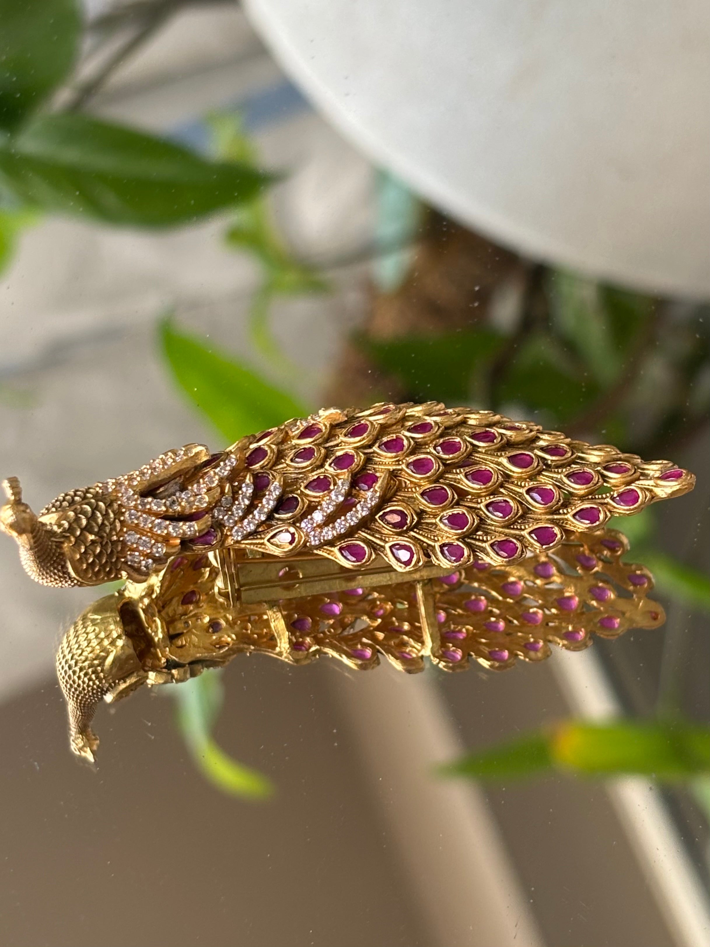 Detail shot of peacock brooch showing layered feather pattern and metallic finish