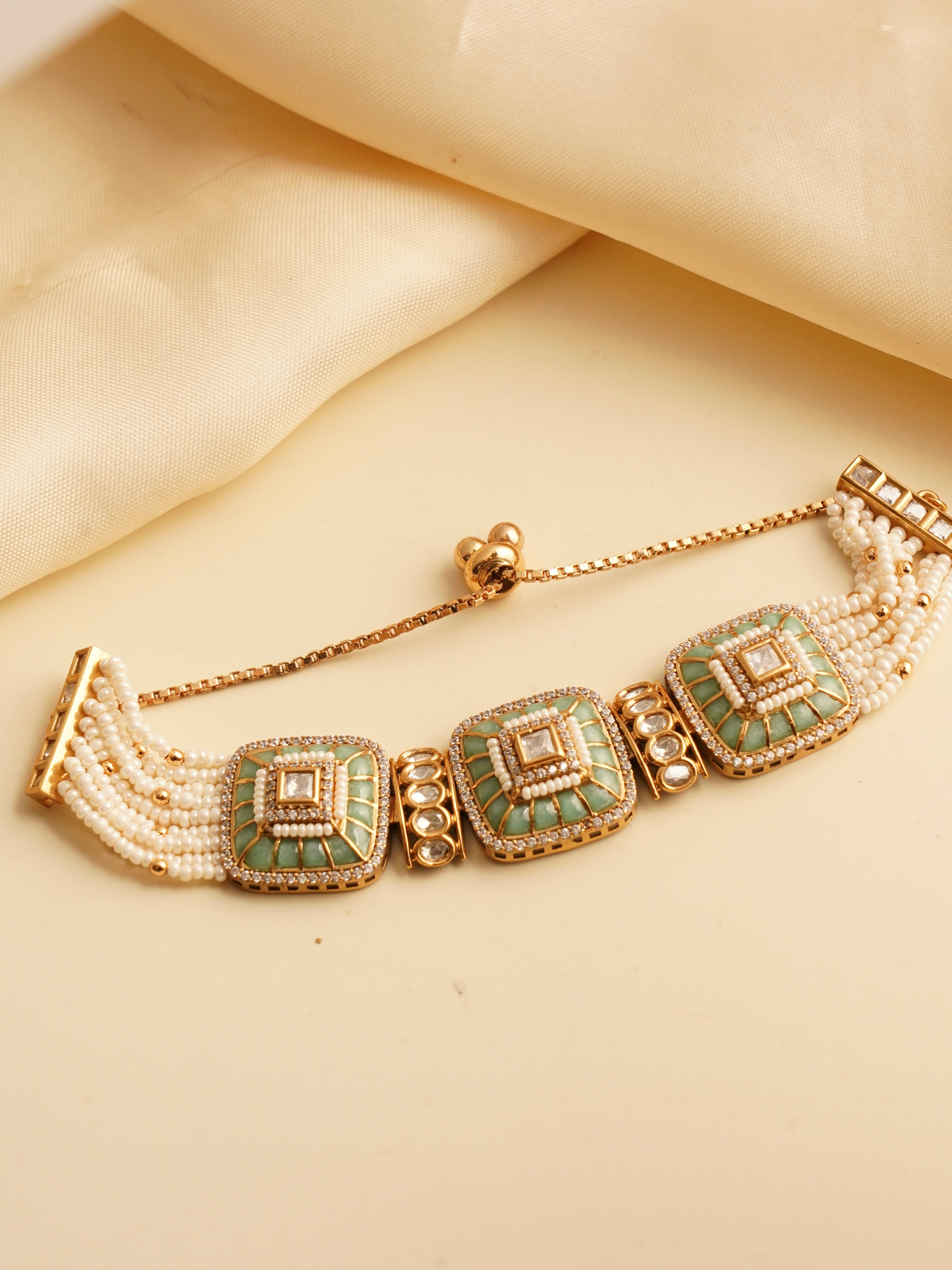 Angled view of openable kundan bracelet with pearls and intricate detailing in gold tone