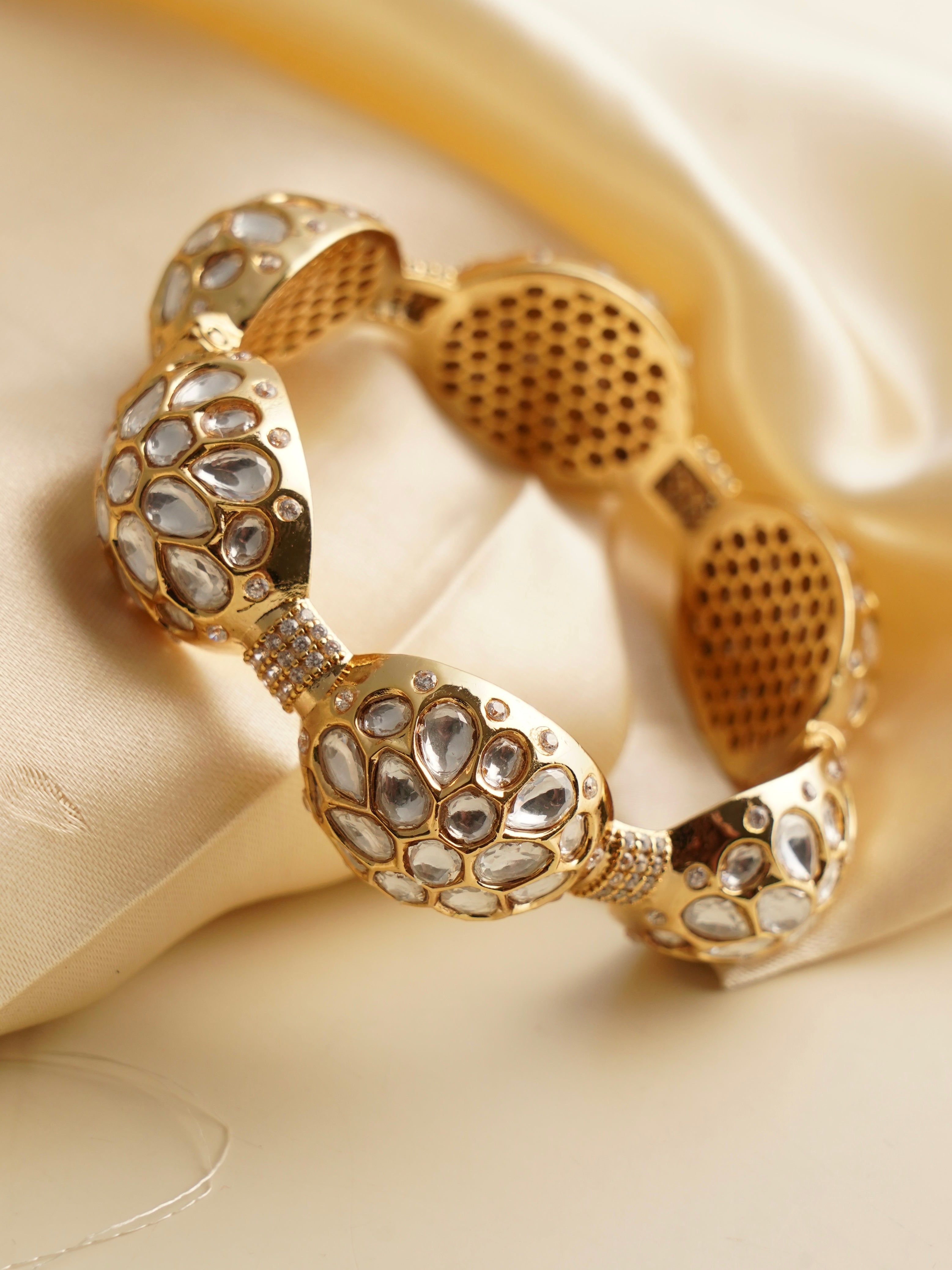 Dome-shaped kundan bangle with gold polish in front angled view