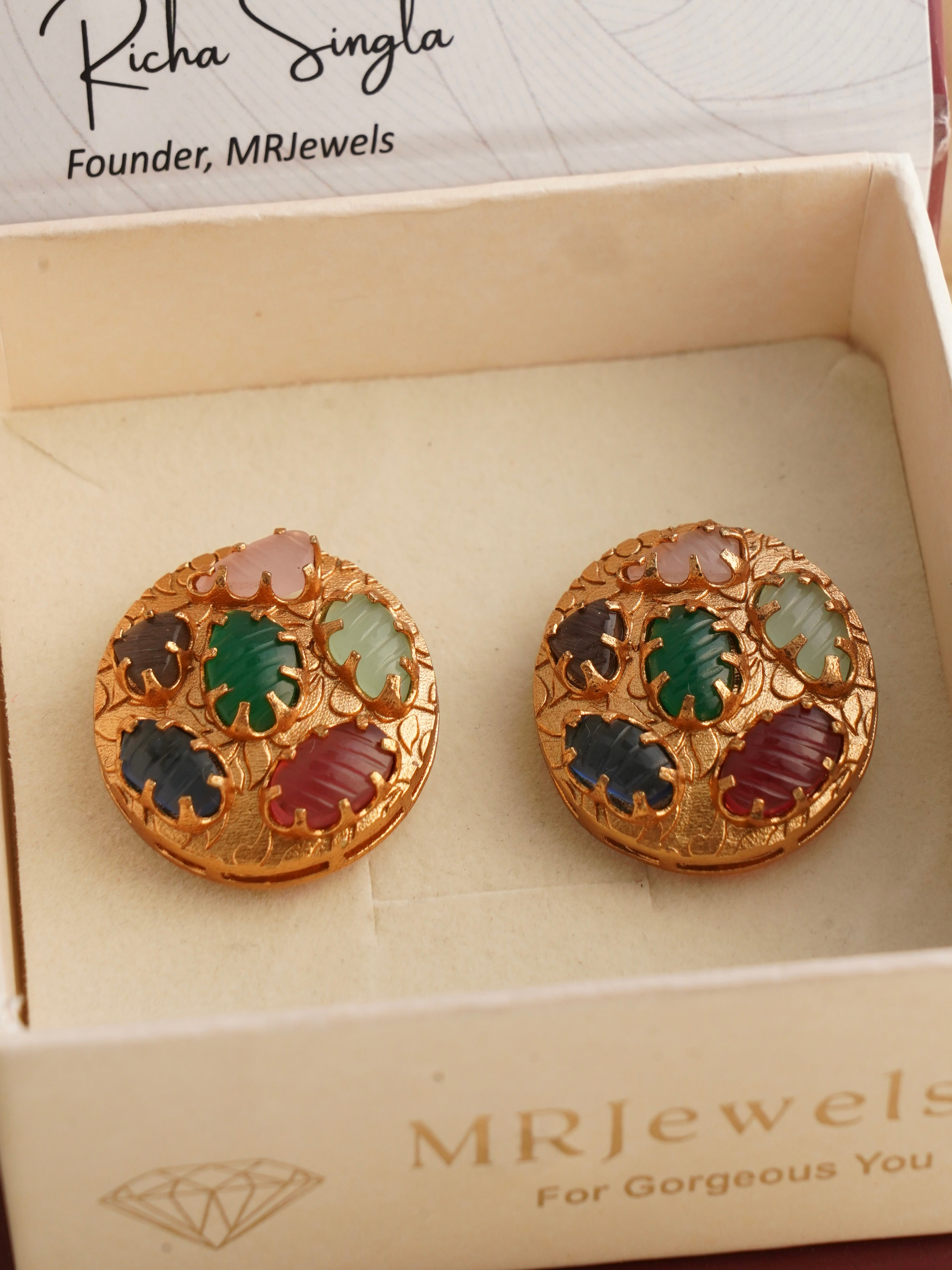 Navratna carved medallion studs with multicolored carved gemstones presented in a jewellery box