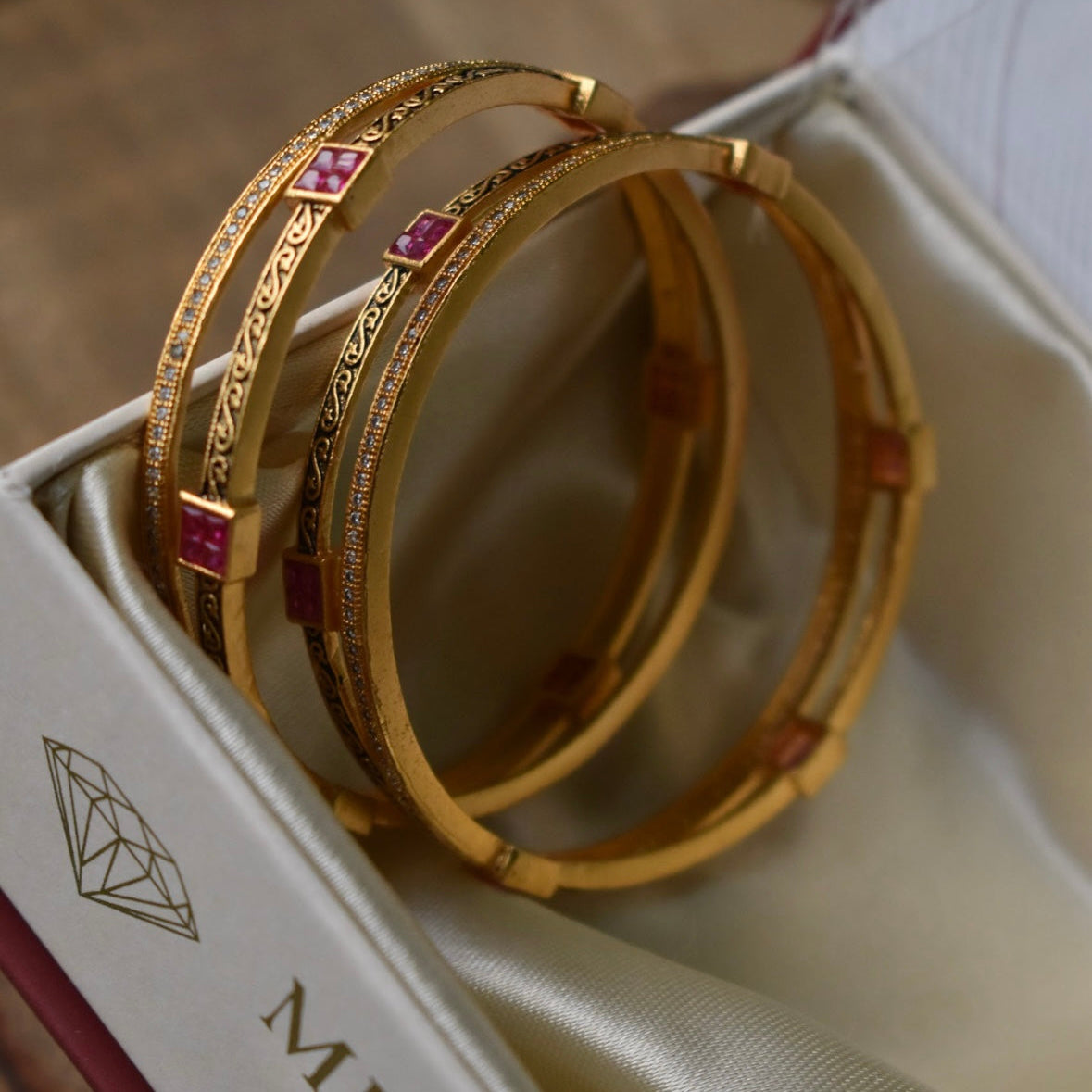 Side view of ruby filigree bangles with enamel accents in gold-tone finish