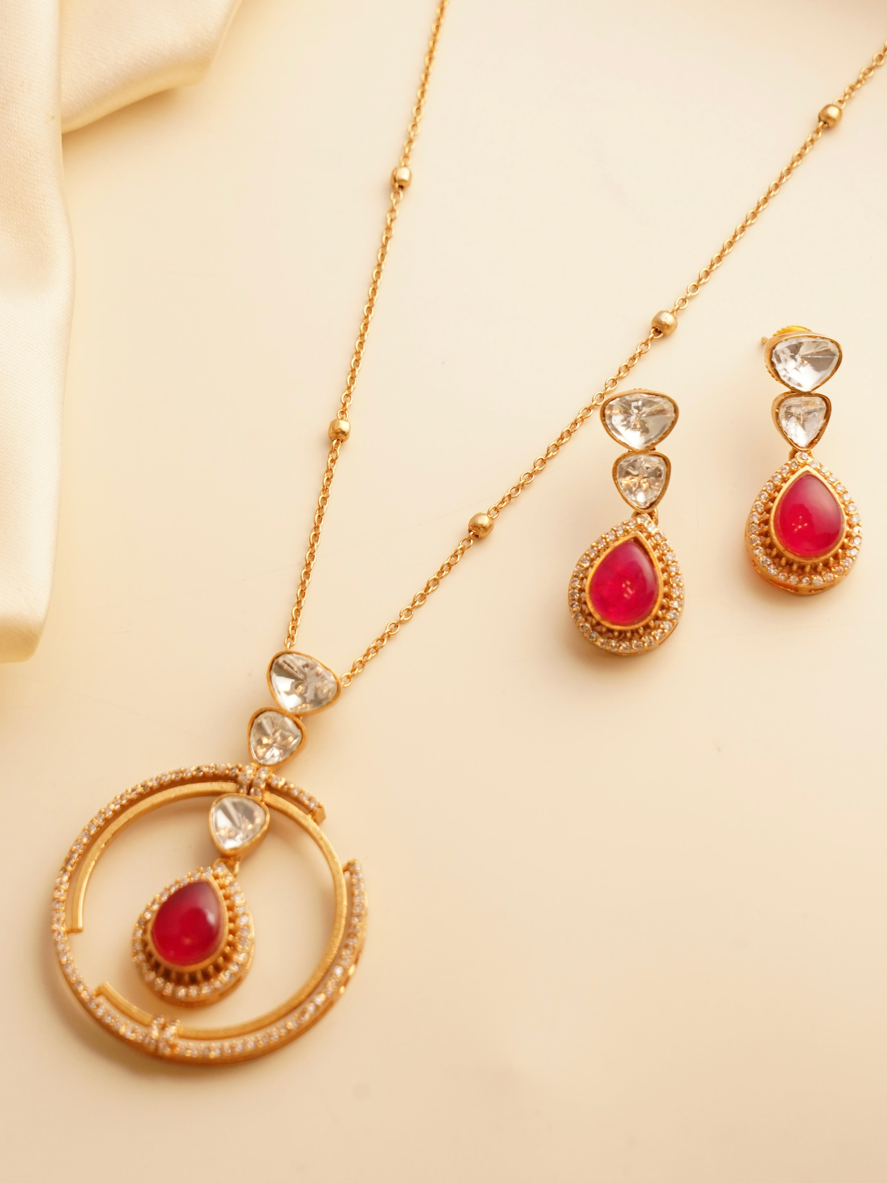 Gold-plated necklace with emerald teardrop pendant, kundan accents, and circular design