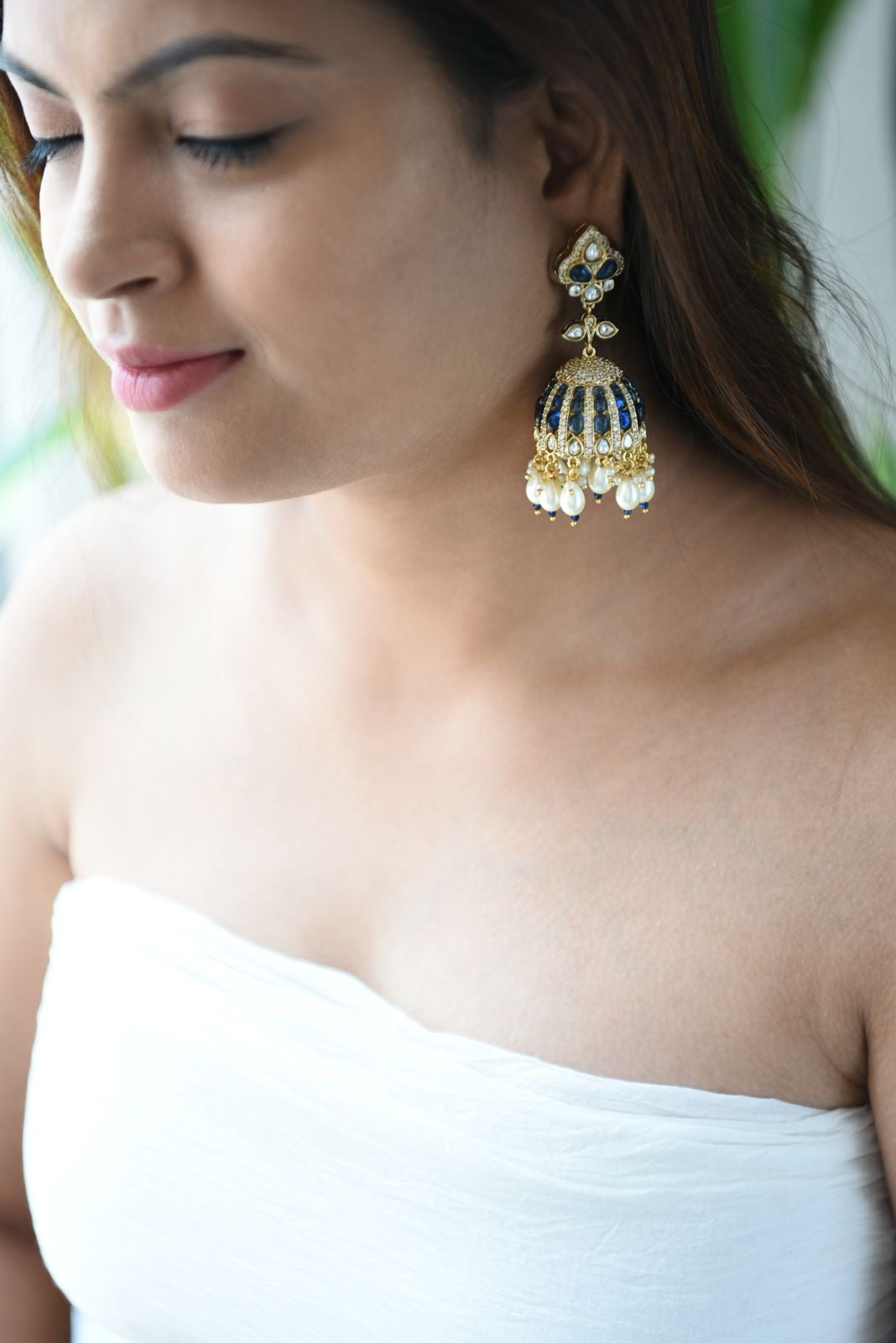 Side view of royal jhumkas featuring intricate gold detailing and gemstone accents