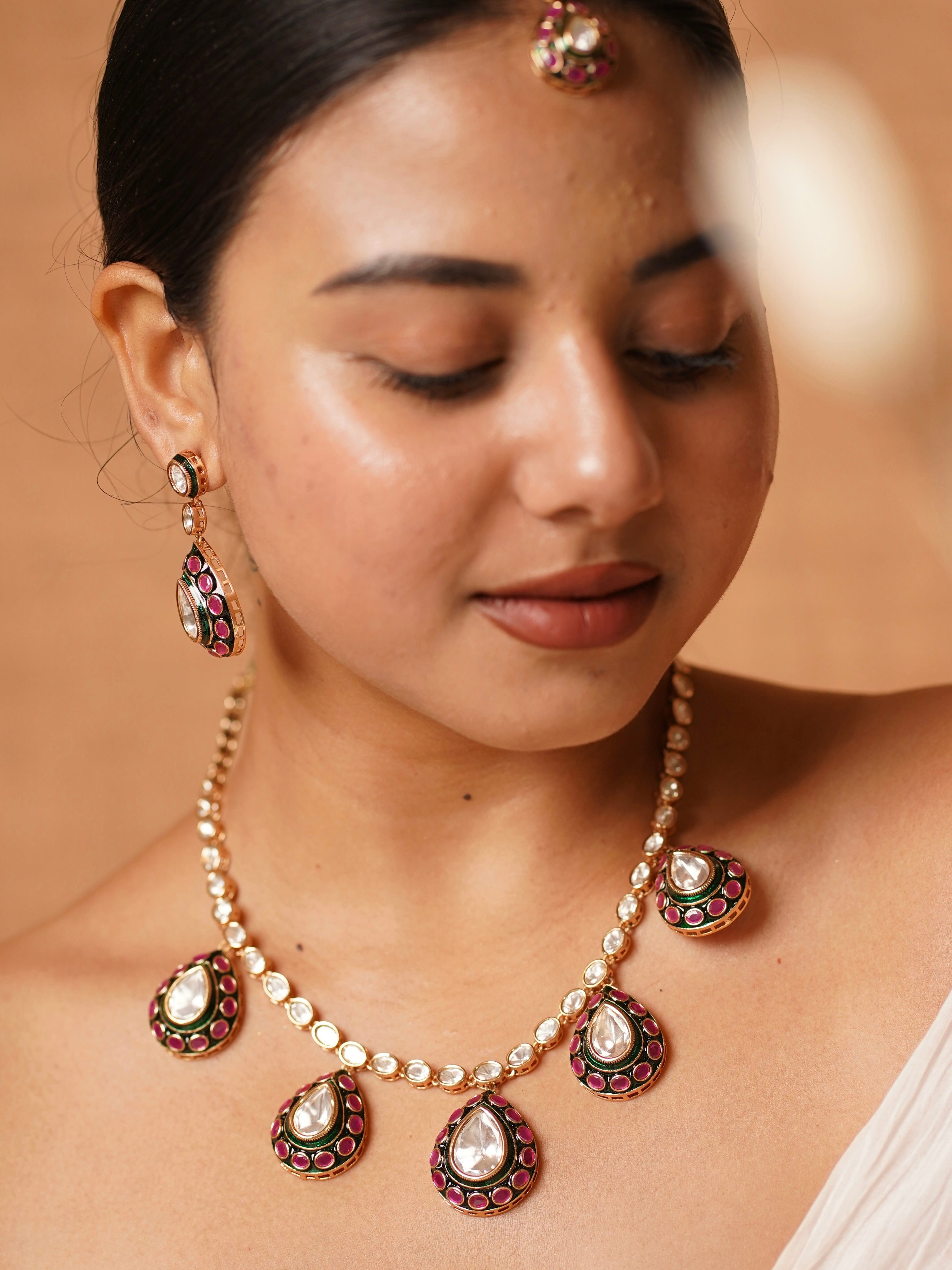 Meenakari necklace with uncut polki stones and pink-green enamel, earrings, and maangtikka