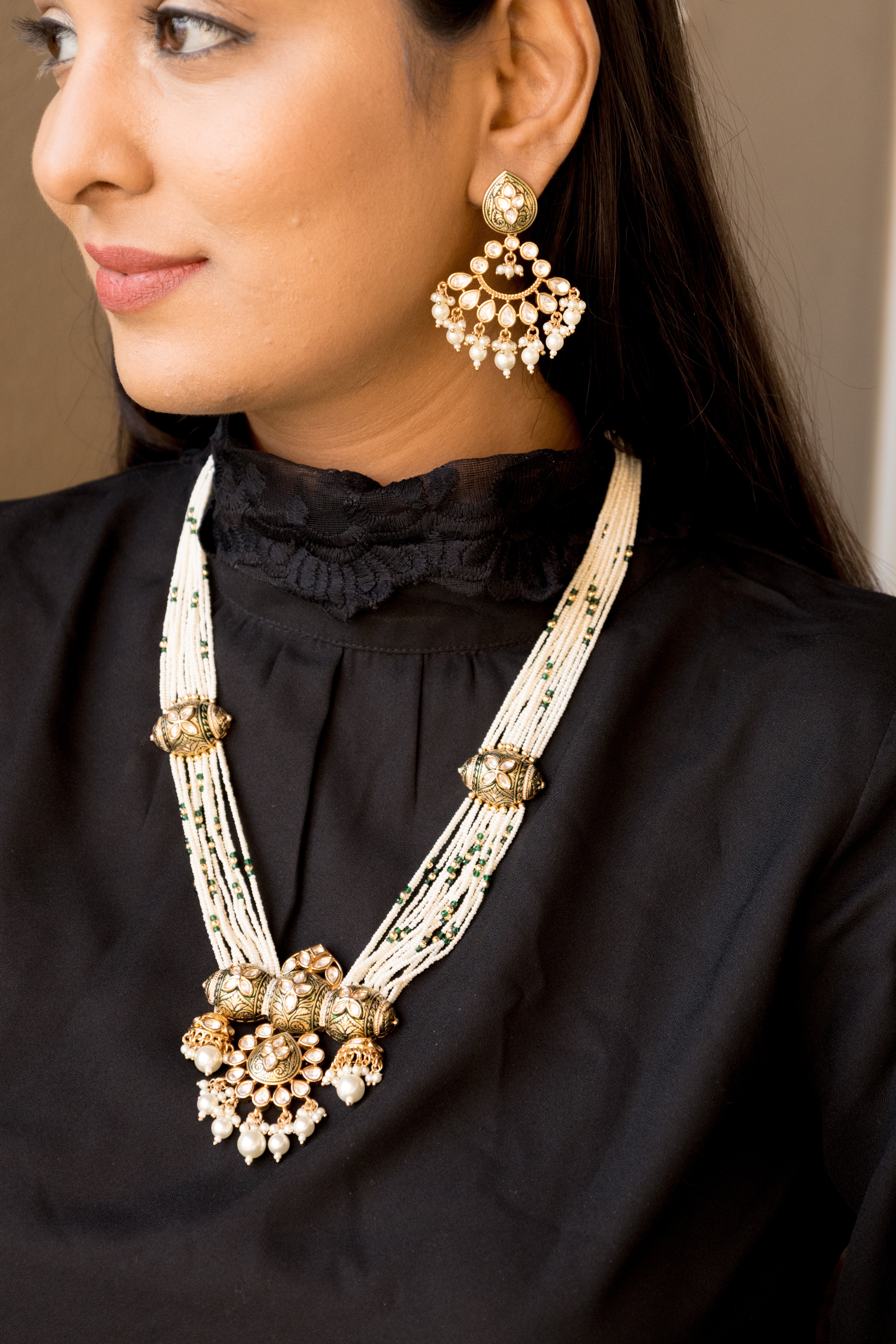 Layered pearl necklace with kundan detailing and gold motifs, paired with drop earrings