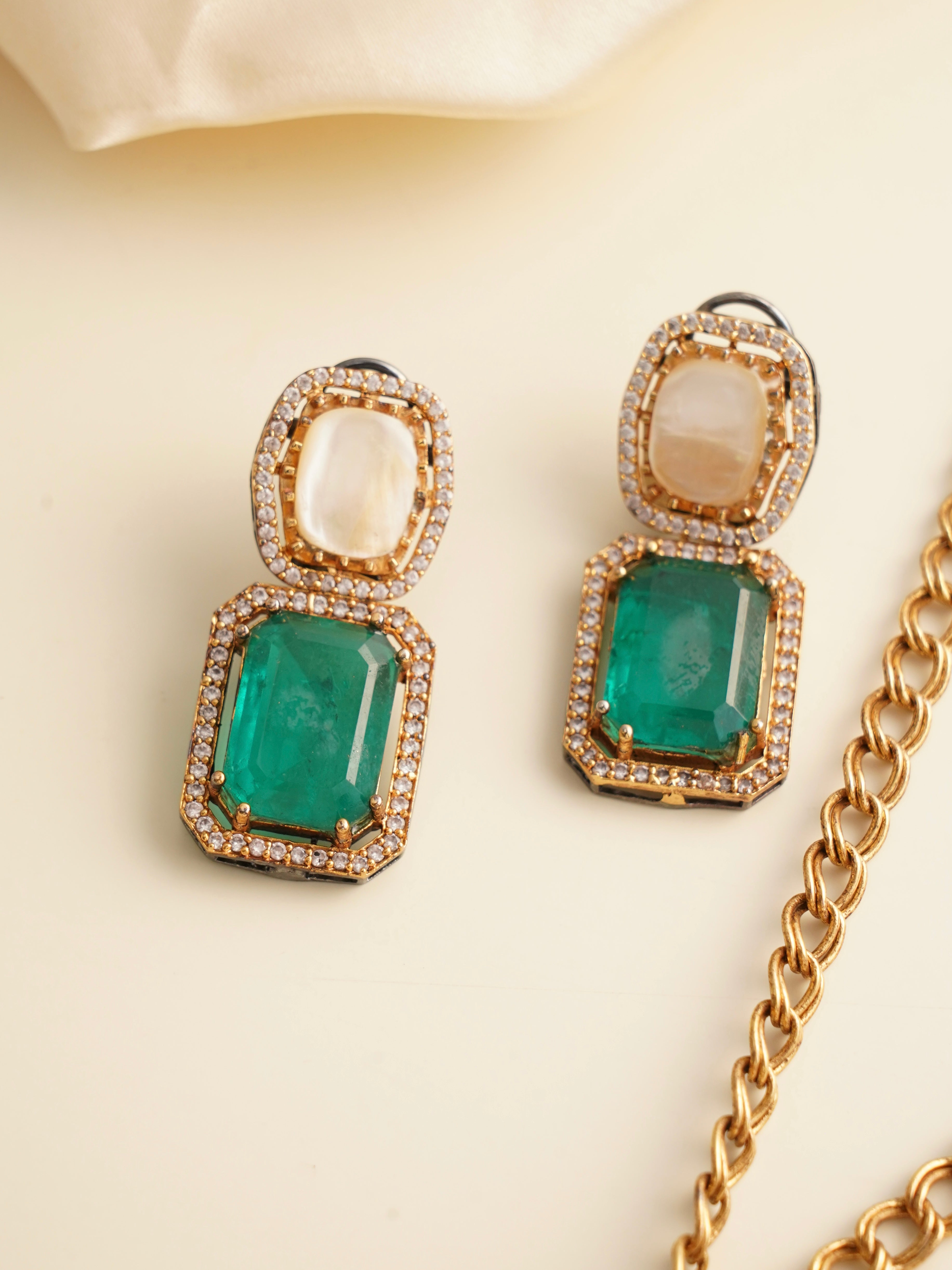 Side angle of emerald pendant and earrings with pearl and stone detailing