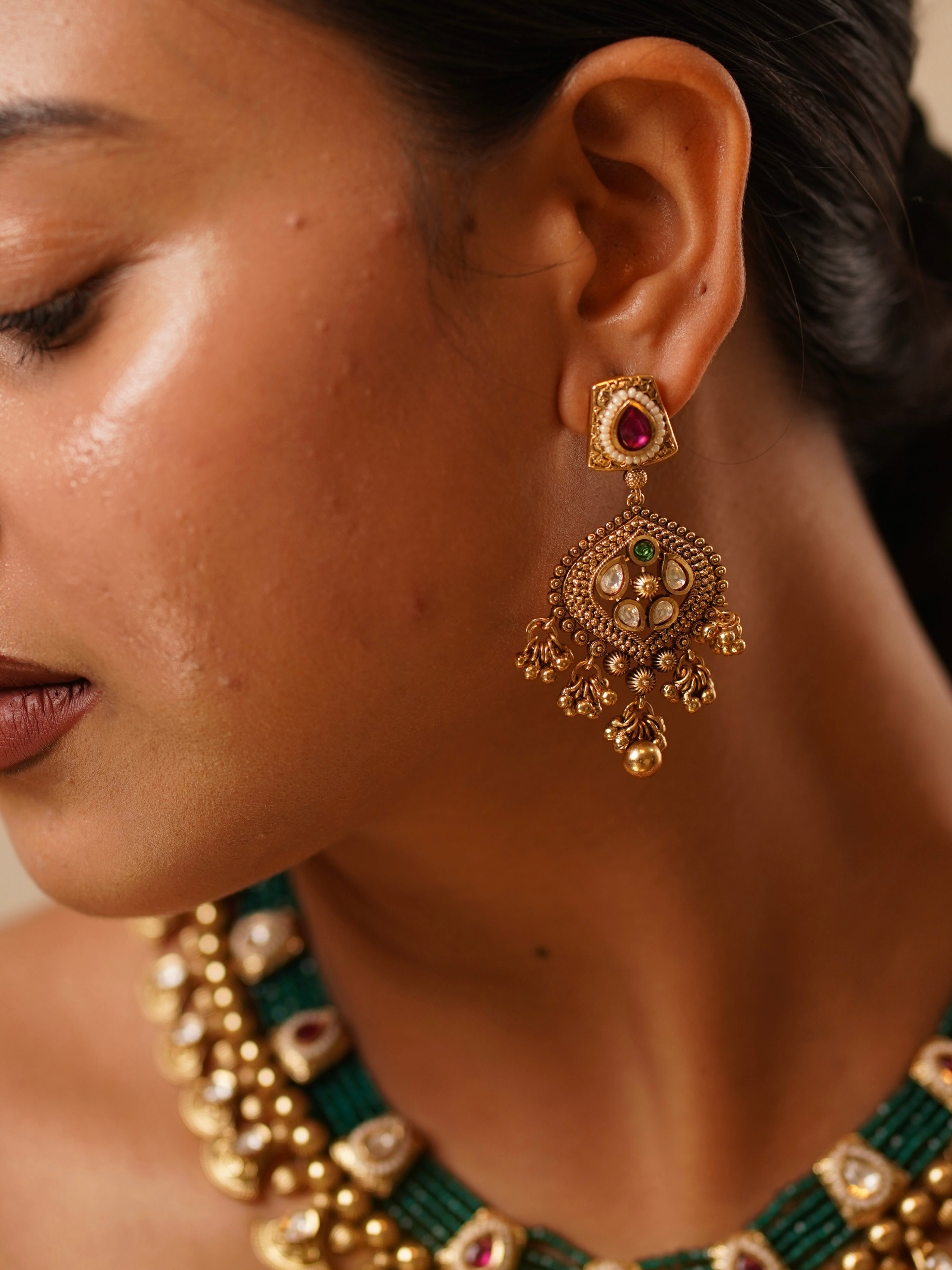 Close-up of ruby-toned earrings with antique gold finish from Meher Empress jewellery set