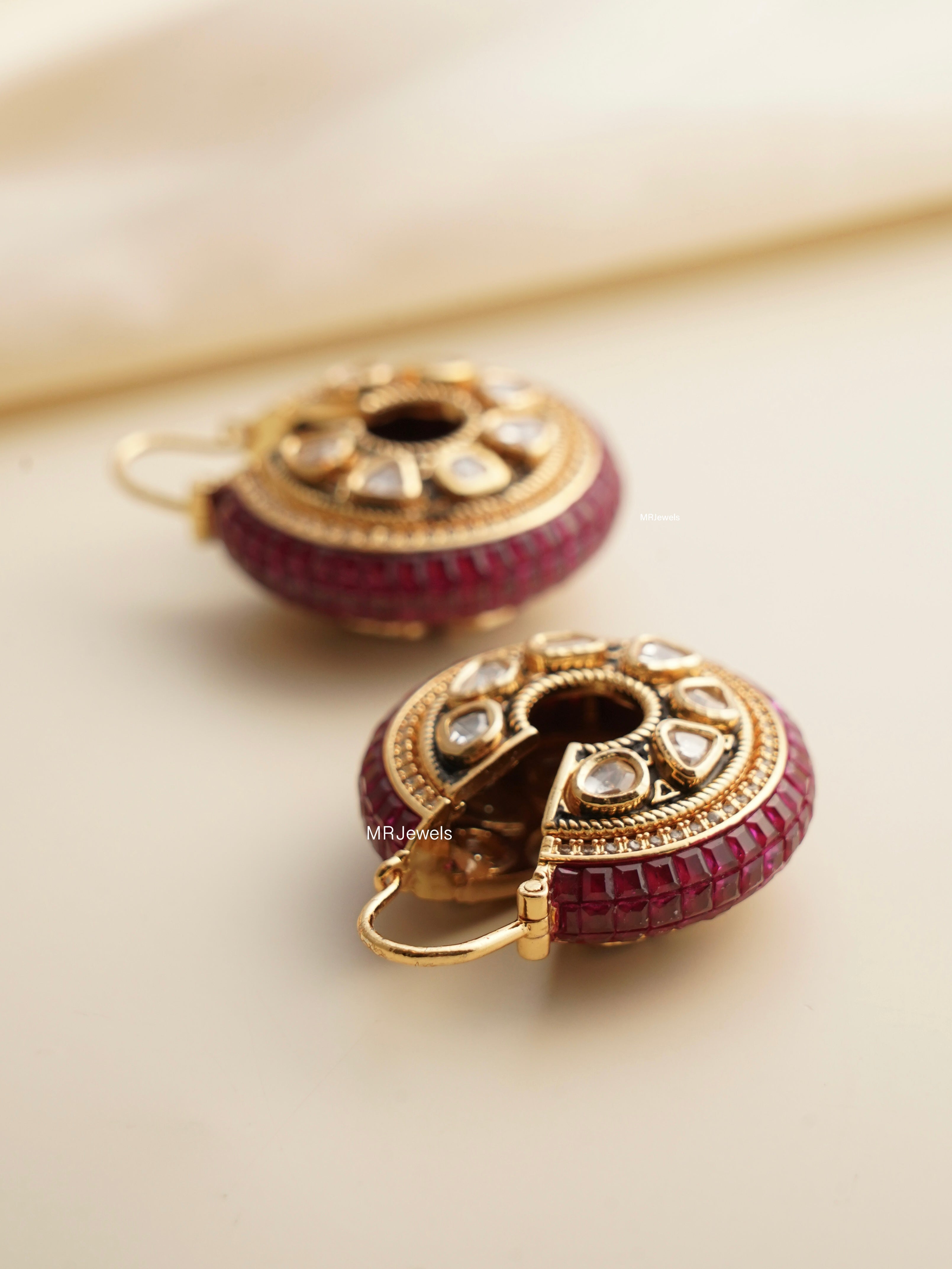 angled view of traditional vilandi earrings with ruby centerpiece and filigree work
