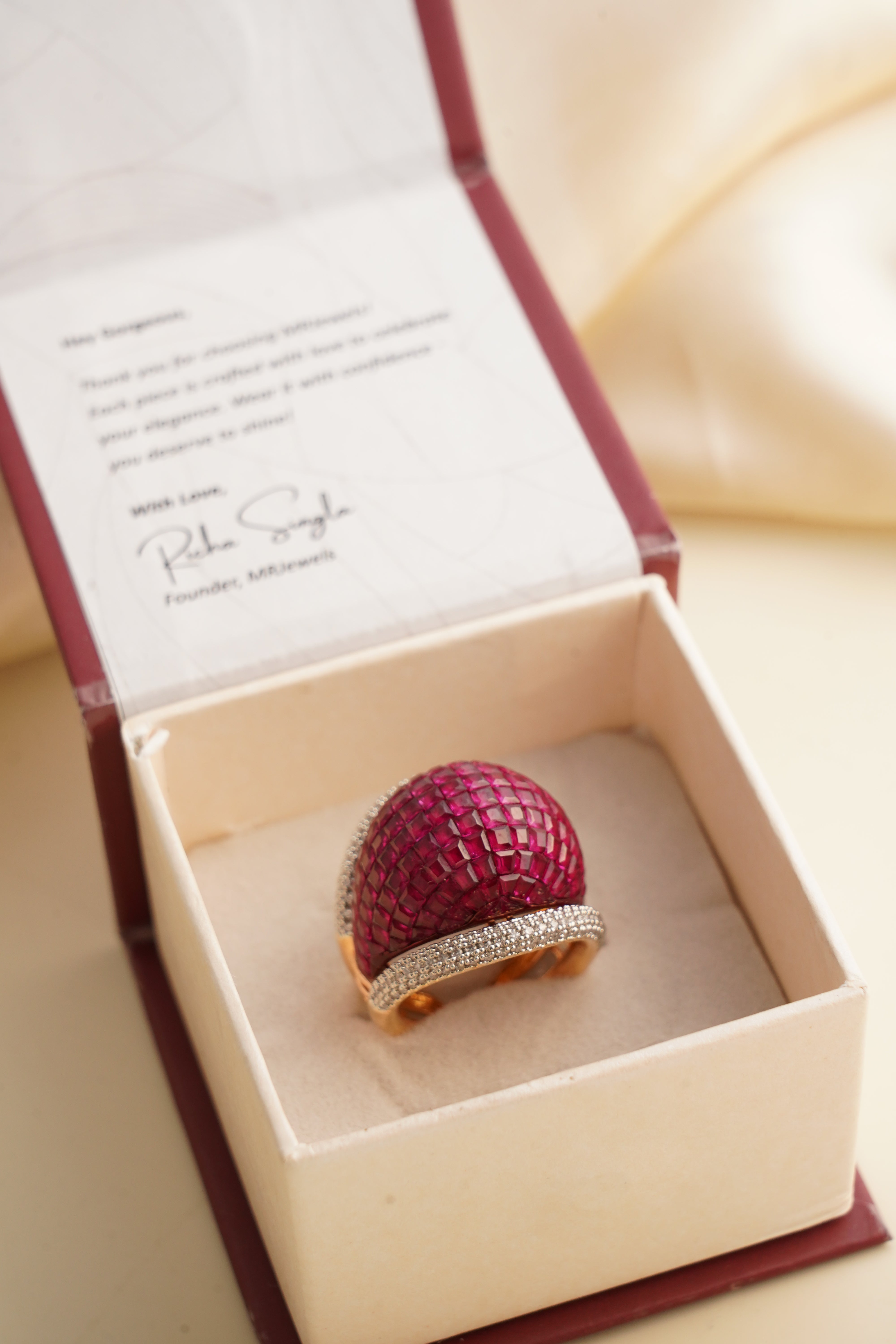 Side view of ruby zircon ring with vibrant red stone and sparkling diamond surround