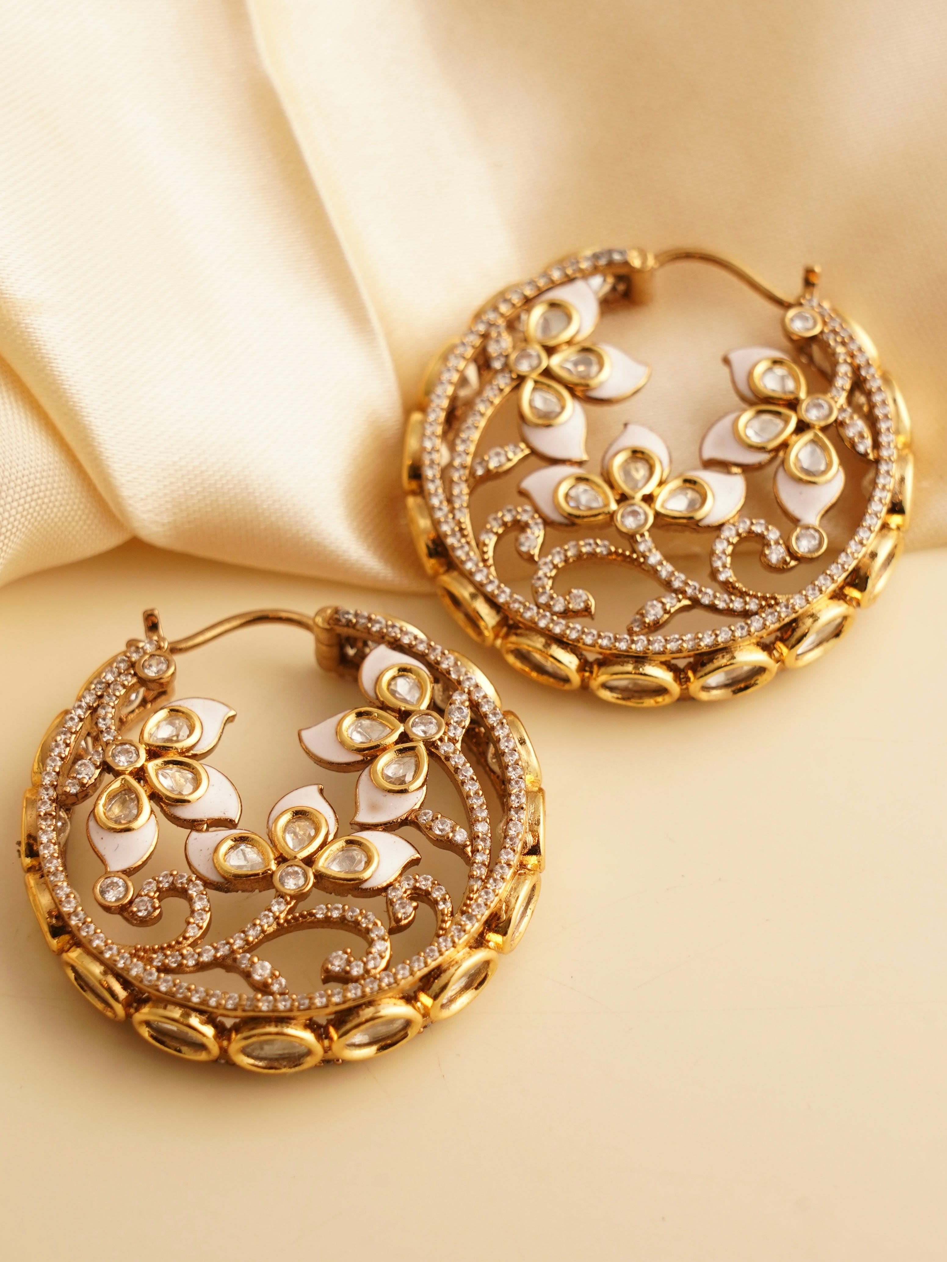 side profile of enamel-accented hoop earrings with gold-toned floral detailing