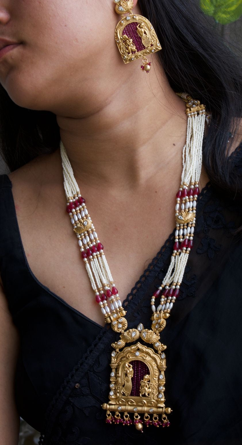 Temple necklace with Radha Krishna pendant, ruby beads, pearl strands, and gold finish