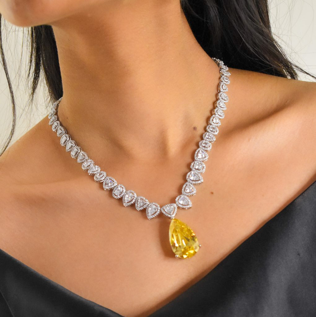 Close-up of pear-shaped yellow diamond pendant surrounded by brilliant-cut stones