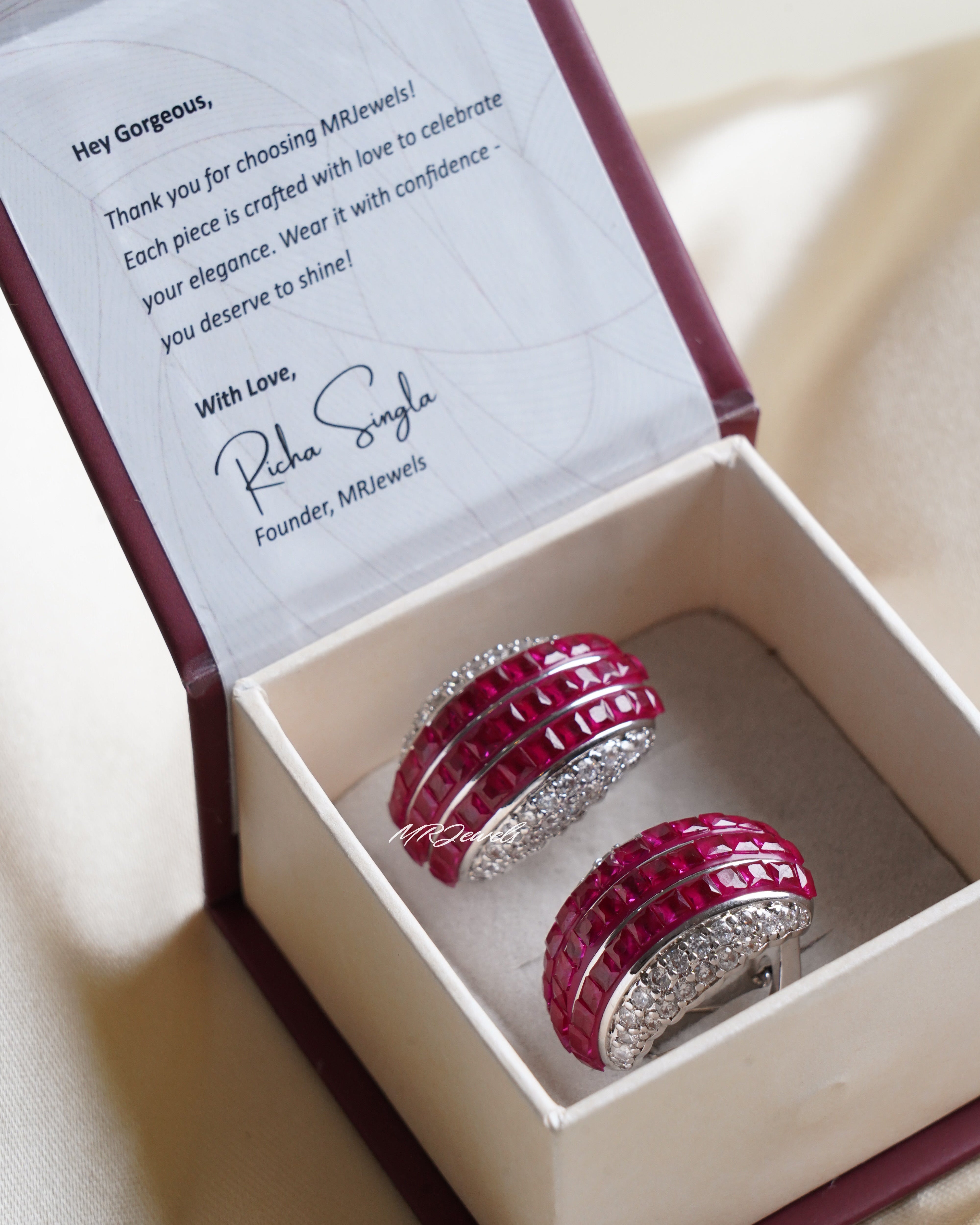 Side profile of ruby and multitone gemstone studs with shimmering CZ halo and bold silhouette