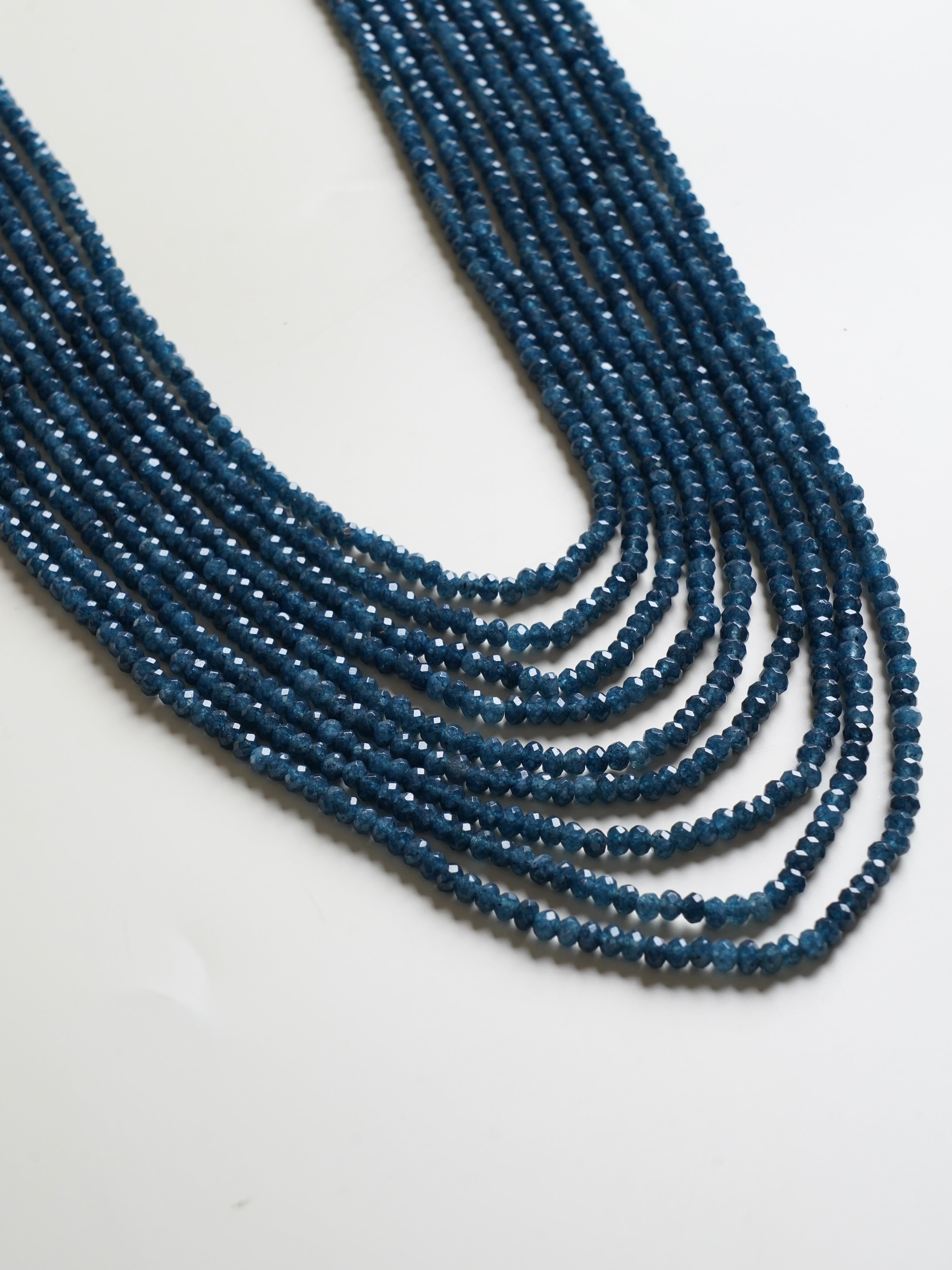 Close-up of faceted gemstone strings in ruby red and emerald green tones