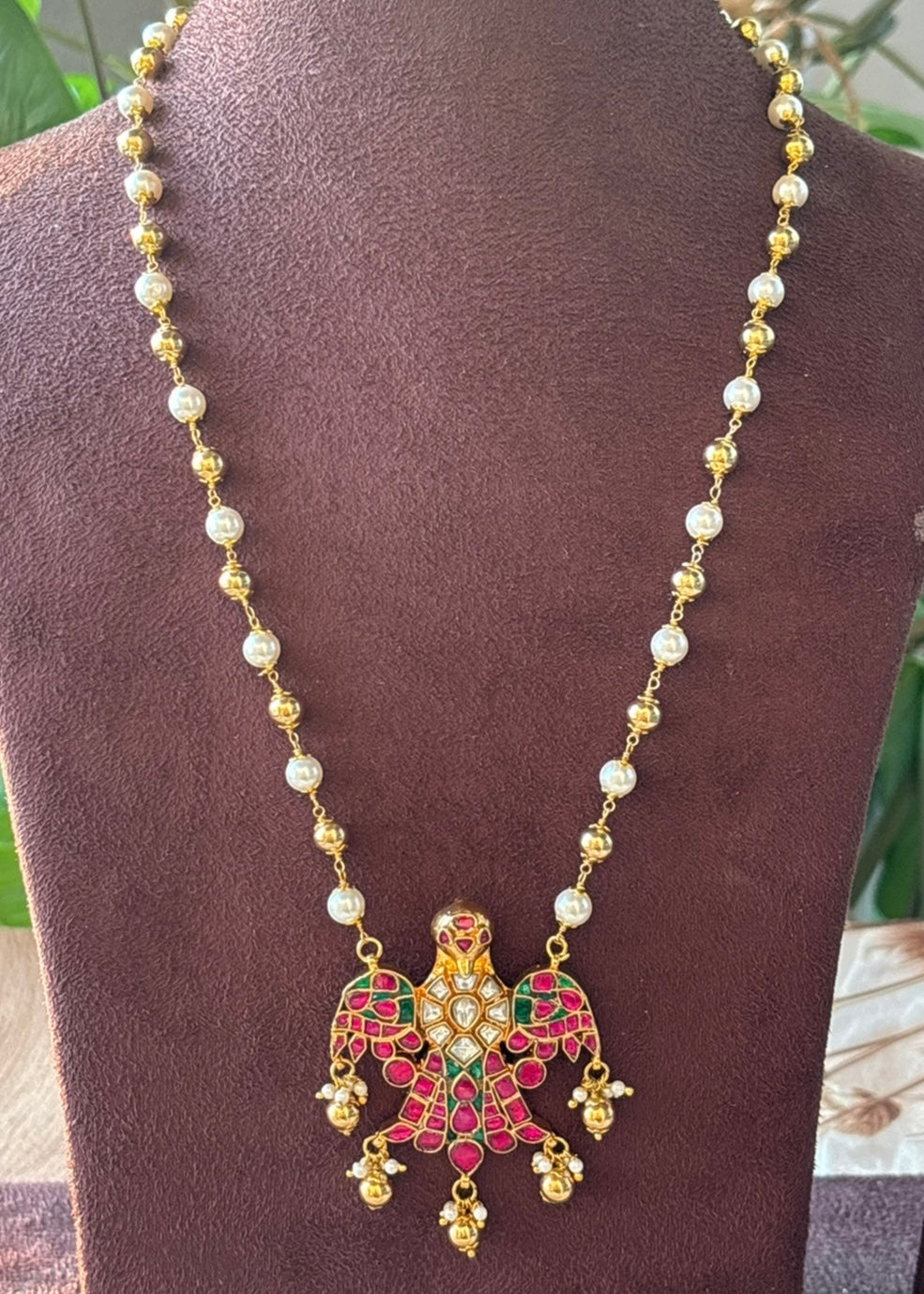 Close-up of jadau pendant showcasing intricate eagle motif with enamel and gold accents