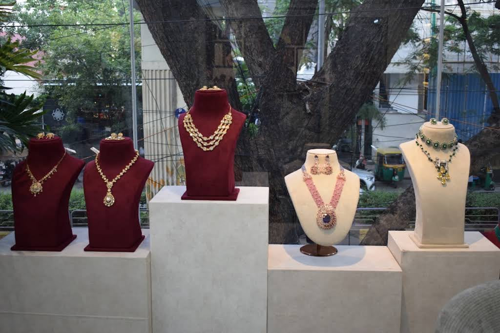 Necklaces displayed on burgundy and cream stands beside the showroom window